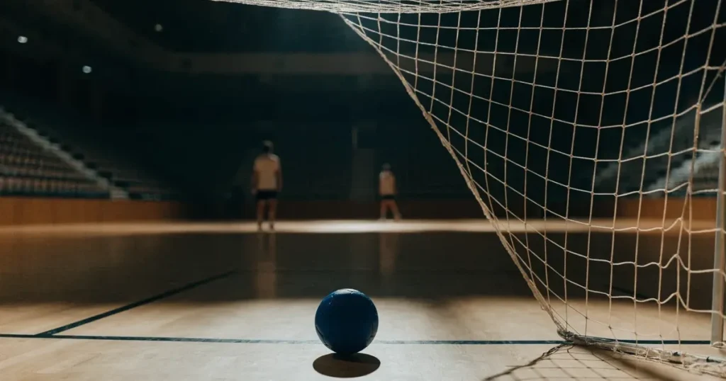 Ein Tor mit dicht gespanntem Netz steht in einer grossen Halle, davor liegt ein Handball auf der Torraumlinie.